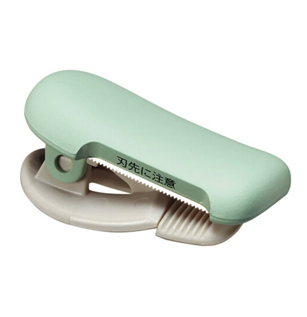 Green and beige washi tape cutter on a white background
