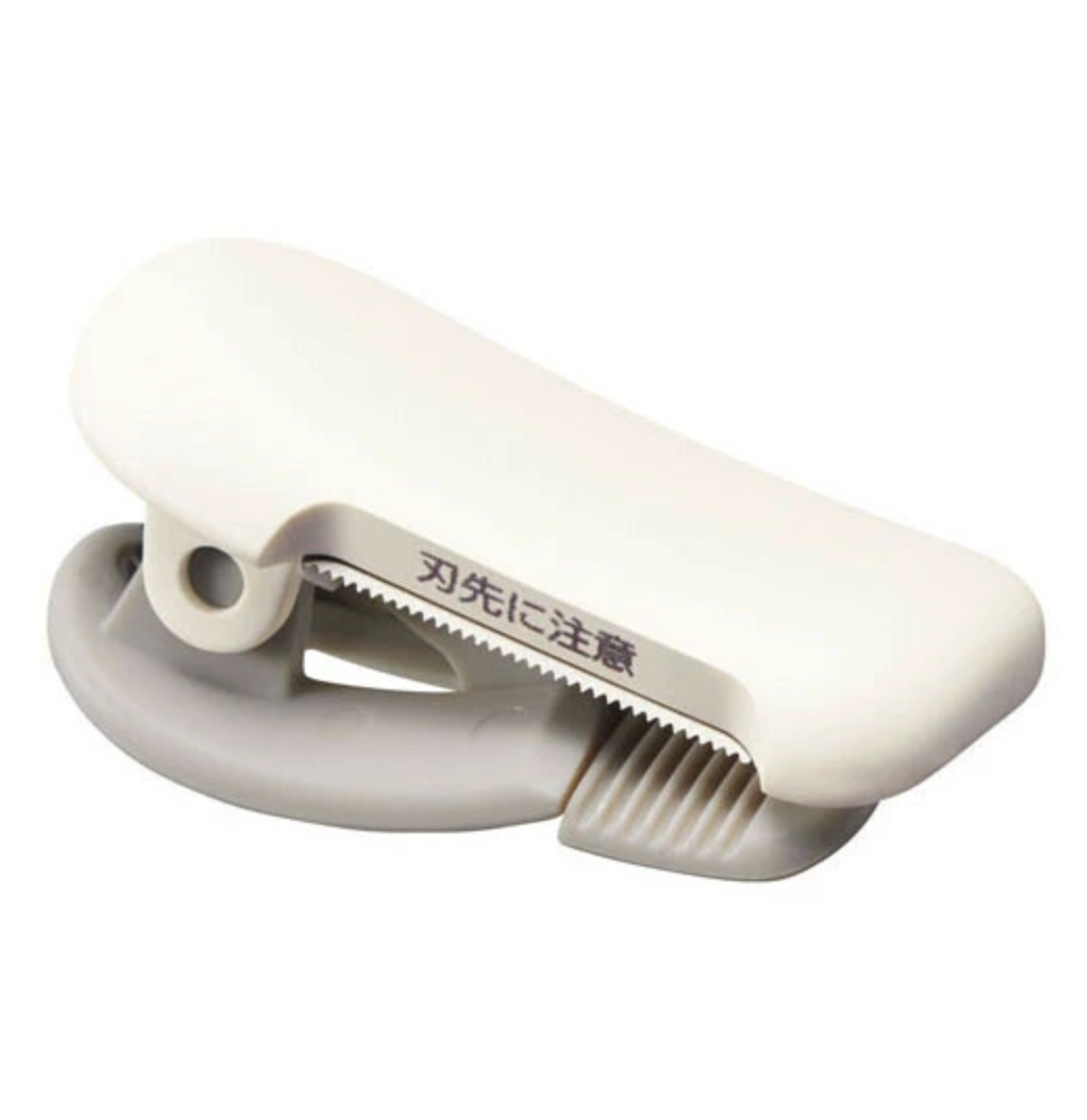 White washi tape cutter with metallic blade on a white background