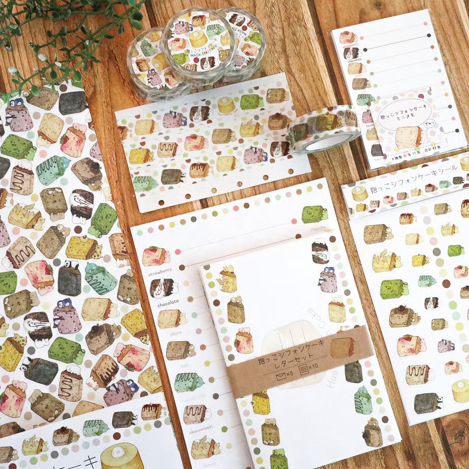 Set of stationery items with cake-themed designs on a wooden surface.