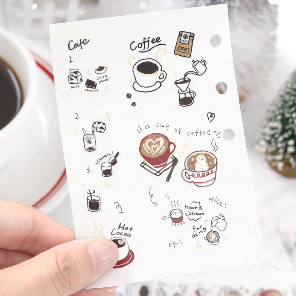 Sheet of coffee-themed stickers held by a hand with a cup of coffee in the background.