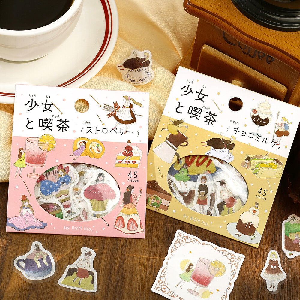 Two packages of illustrated stickers on a wooden surface with a cup of coffee.