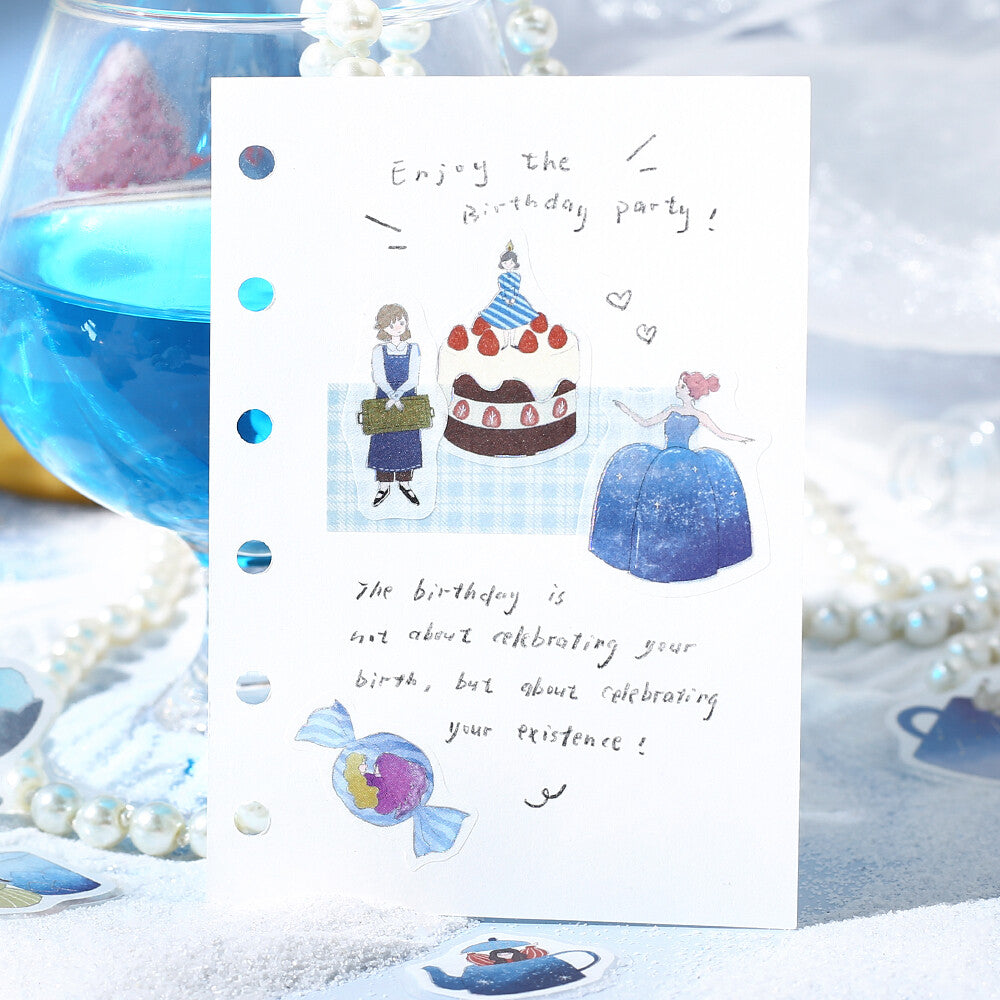 Greeting card with birthday illustration and text, placed on a decorative surface with pearls and a glass bowl.
