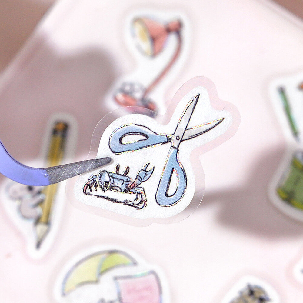 Sticker with scissors cutting a lobster, surrounded by other stickers on a pink background