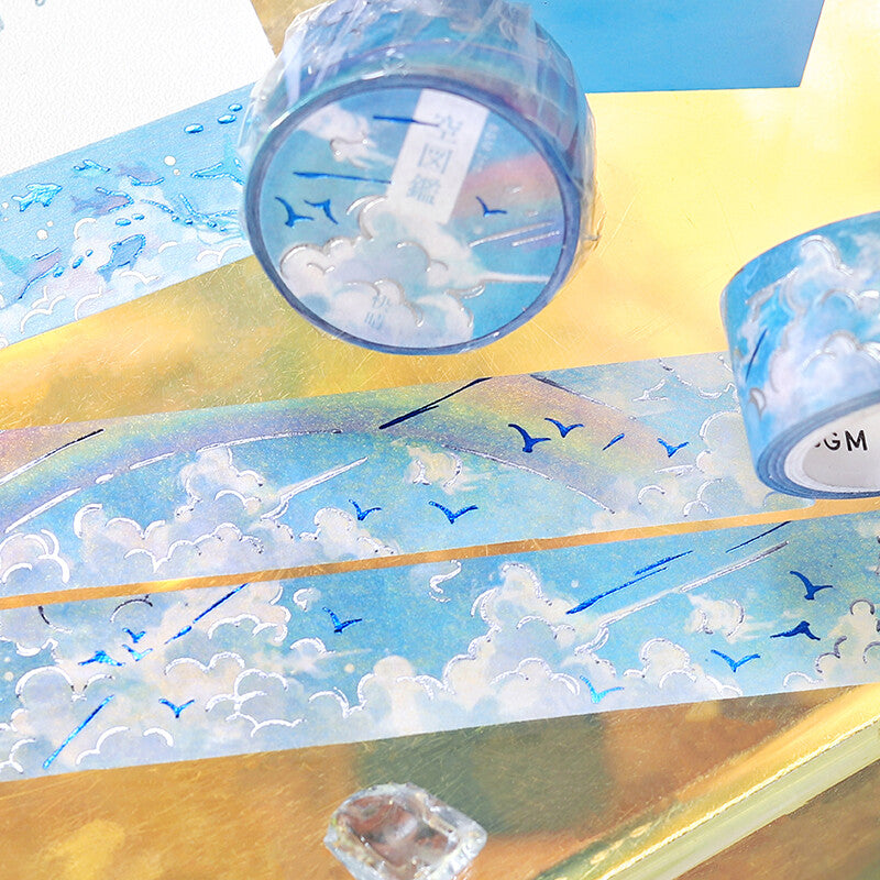 Two rolls of decorative tape with cloud and blue sky design on a colorful background