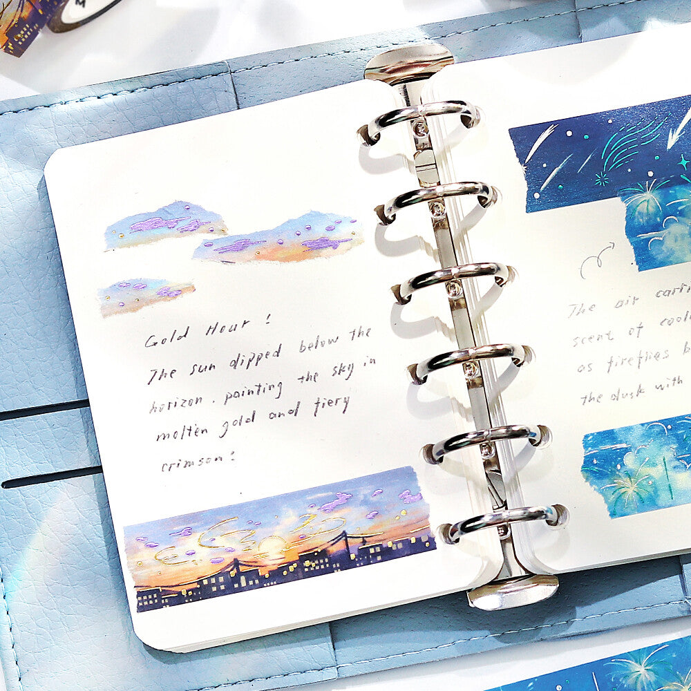 Open planner with scenic stickers on a blue surface