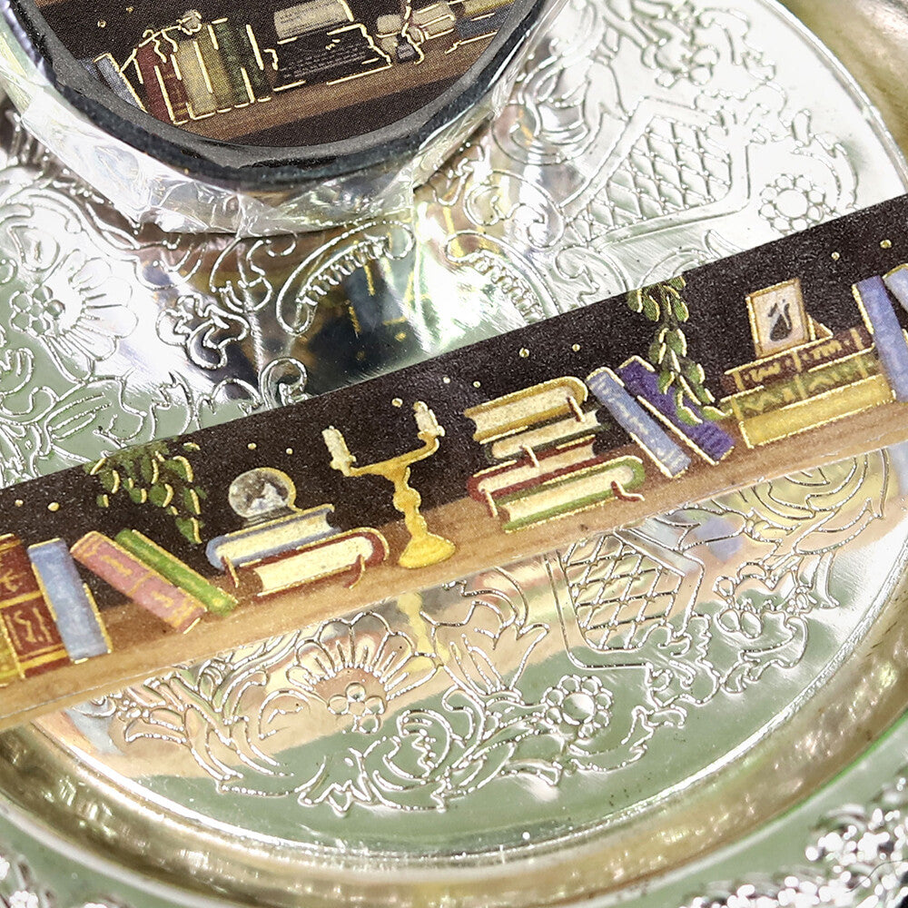 Decorative object with books and candle on a reflective surface