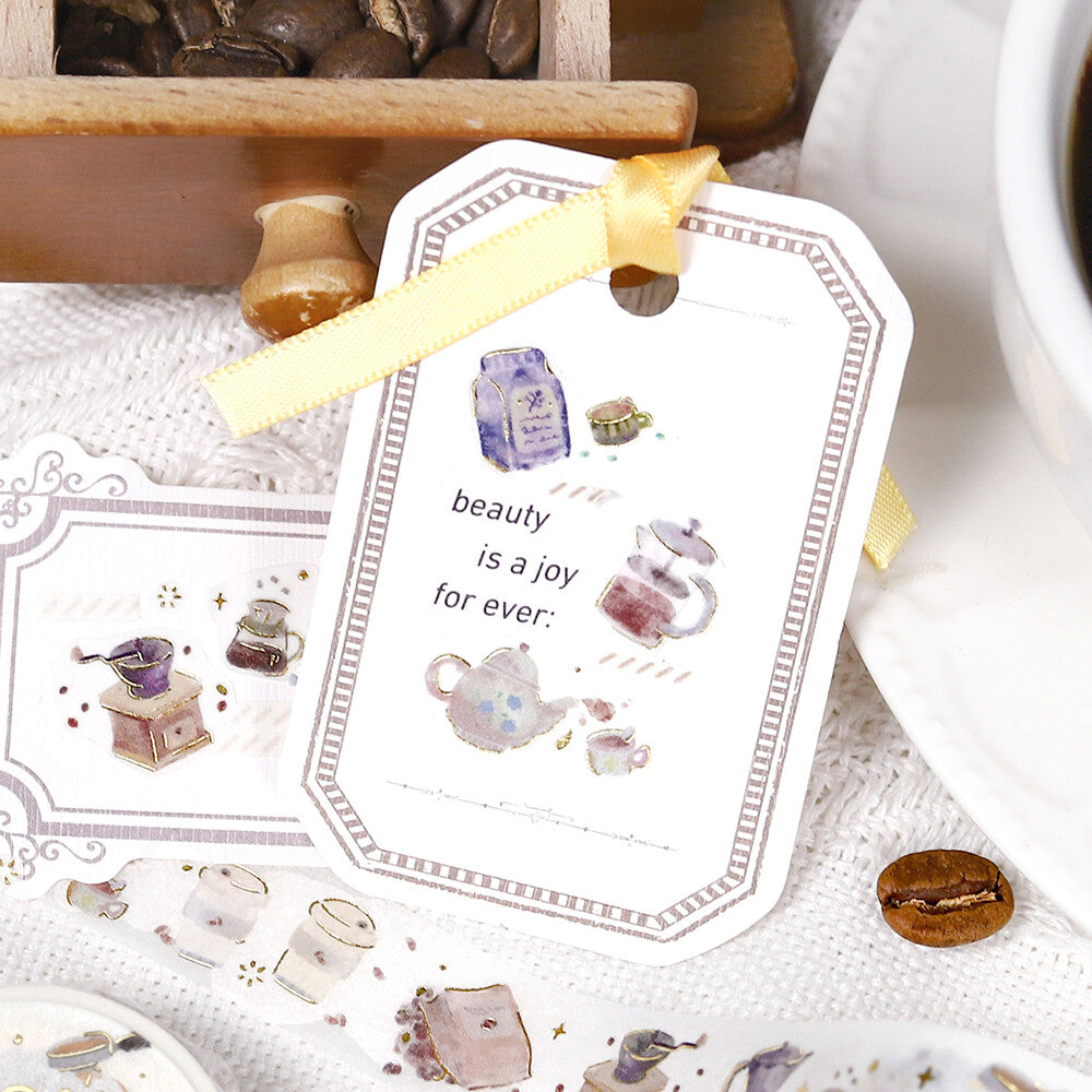 Decorative stickers with tea-themed designs and a motivational quote on a surface with coffee and a teapot.