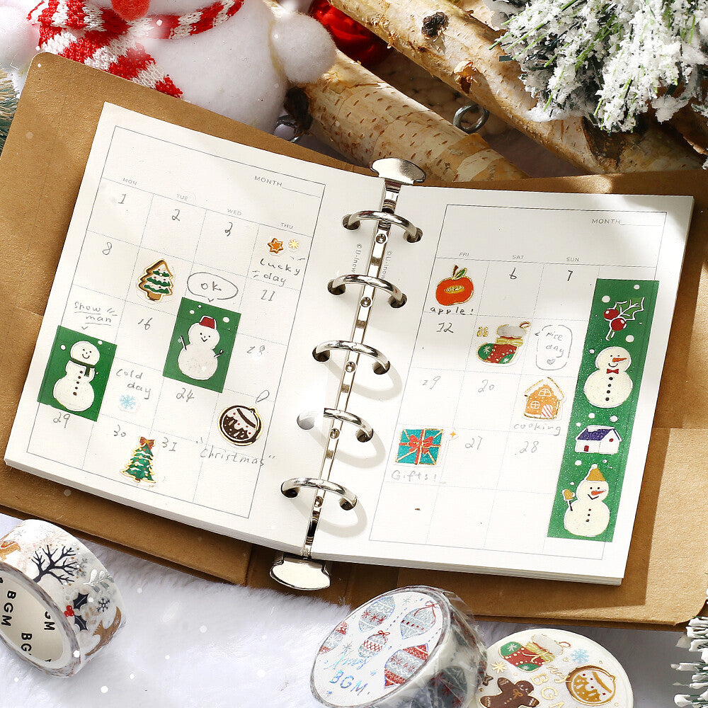 Open planner with Christmas-themed stickers on a decorative surface