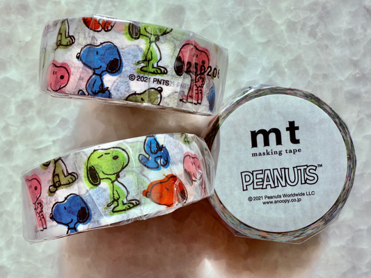 Two rolls of Peanuts-themed masking tape with a circular container labeled 'mt' on a textured surface.