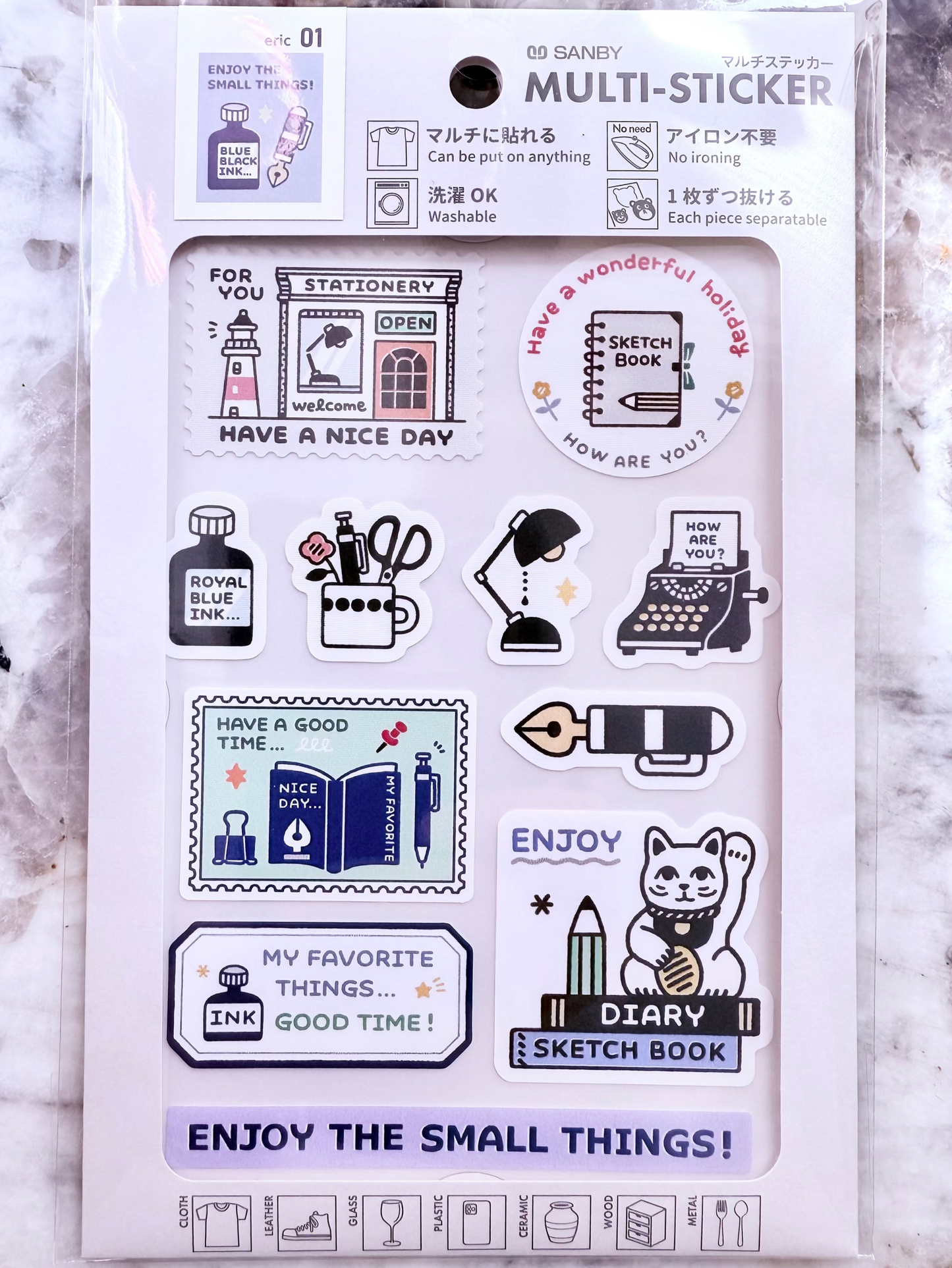 Packaging of a set of stickers with various designs on a marble surface