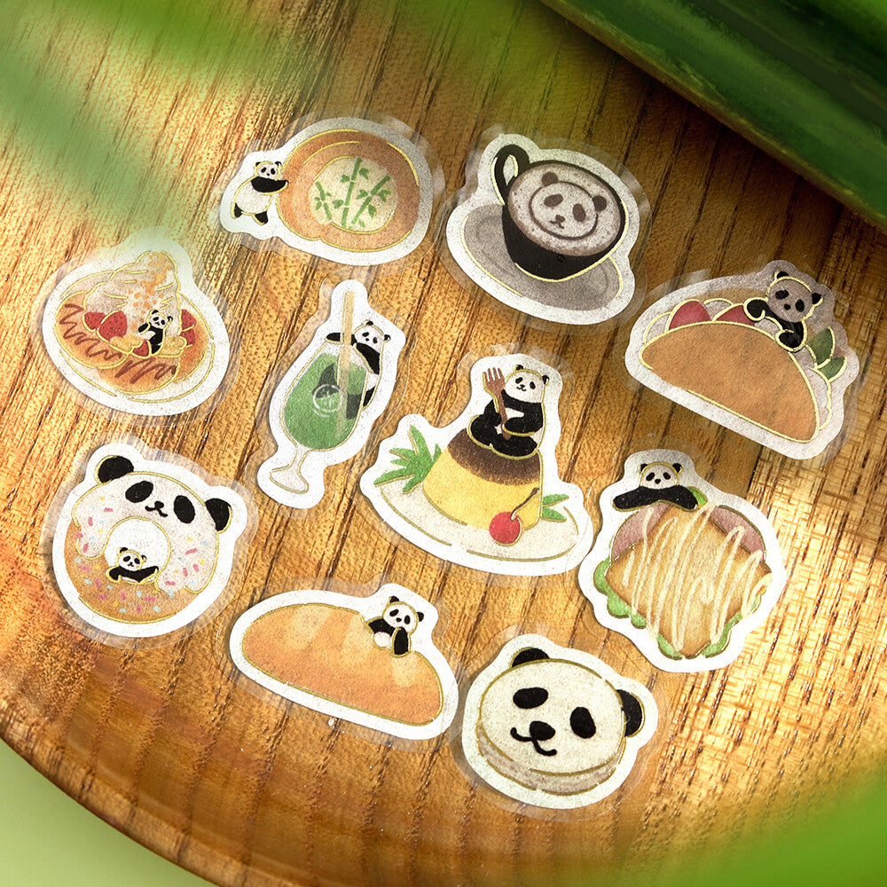 A set of cute die-cut stickers featuring pandas in various food-themed illustrations, arranged on a wooden surface with a green leaf in the foreground.