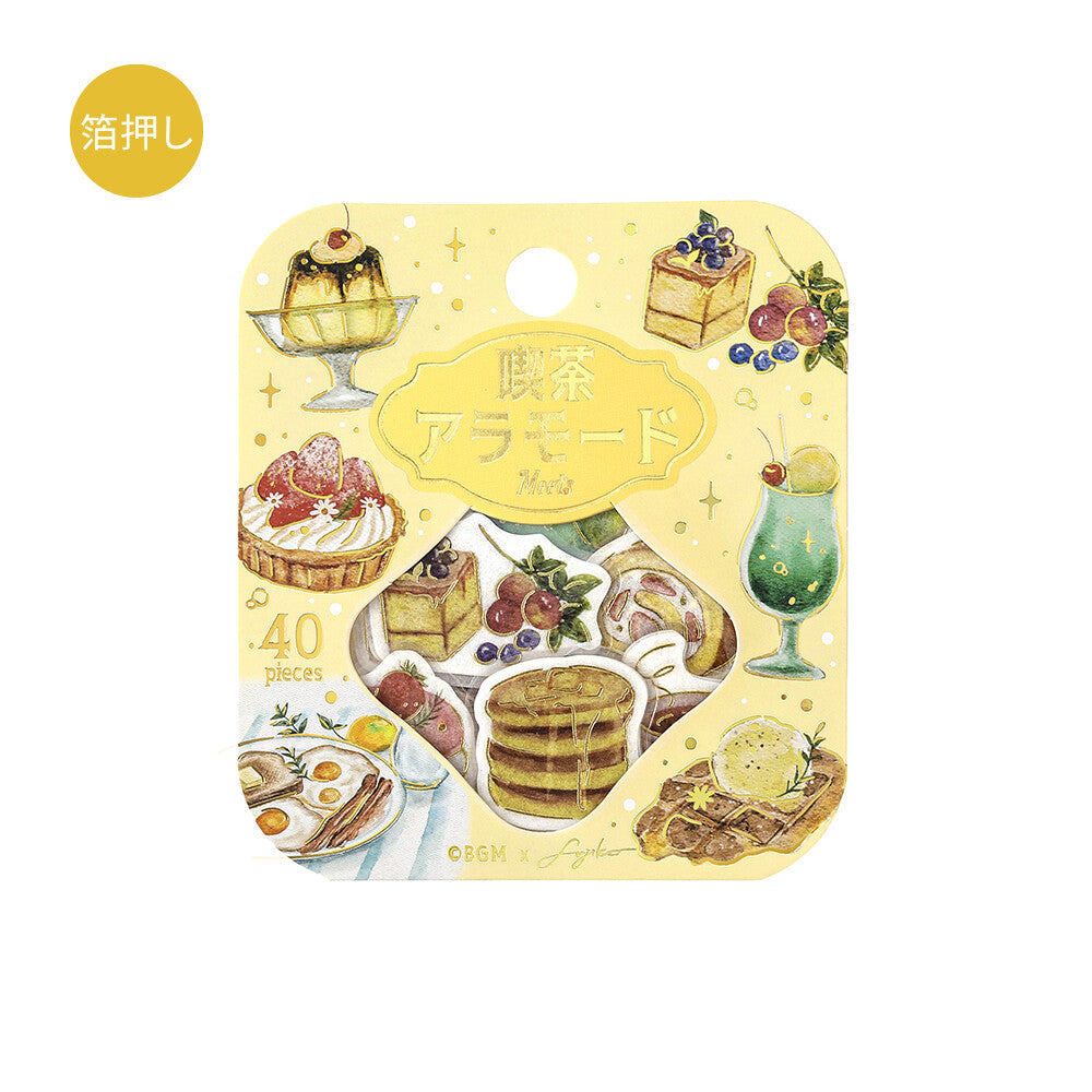 Japanese breakfast-themed sticker pack in its original packaging, featuring illustrations of pancakes, cakes, fruit, and a green drink on a pale yellow card with Japanese text.