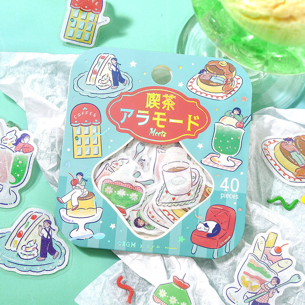 A package of 40 cute tea-themed stickers on a light green background, surrounded by loose stickers. The packaging features a light blue background with illustrations of a cup of tea, cakes, a coffee shop, and a red armchair, with Japanese text '喫茶アラモード Meets' and '40 pieces'.