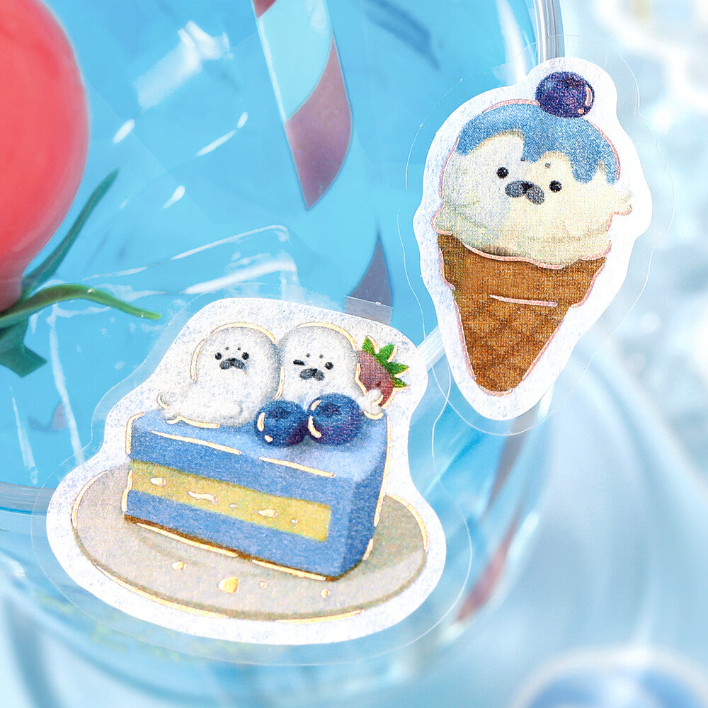 Two cute die-cut stickers featuring cartoon polar bear desserts: a blue cake slice with two polar bears and blueberries, and an ice cream cone with a polar bear face, shown on a glossy blue background.