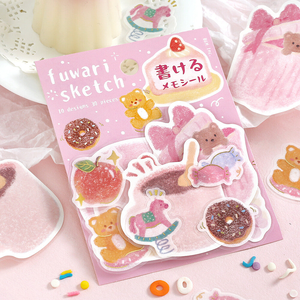 A pink sheet of cute illustrated memo stickers labeled 'fuwari sketch' is arranged on a pastel pink surface with additional matching sticker pieces and decorative props around it.