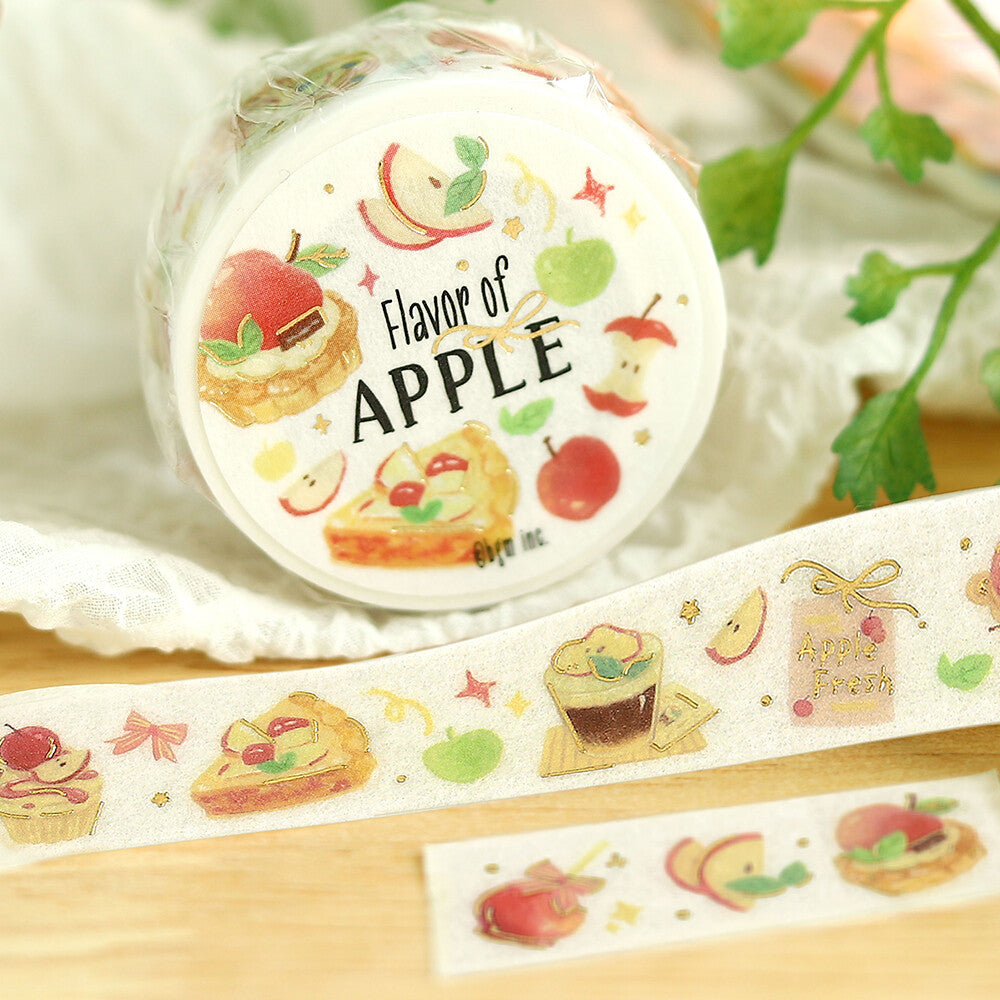 Roll of decorative tape with apple-themed designs on a wooden surface.