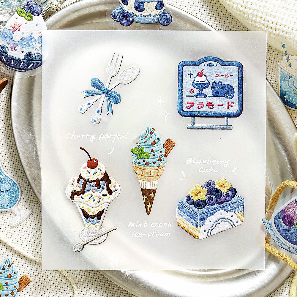 A textured sheet of dessert-themed cake stickers from BGM Inc. is displayed on a metal plate