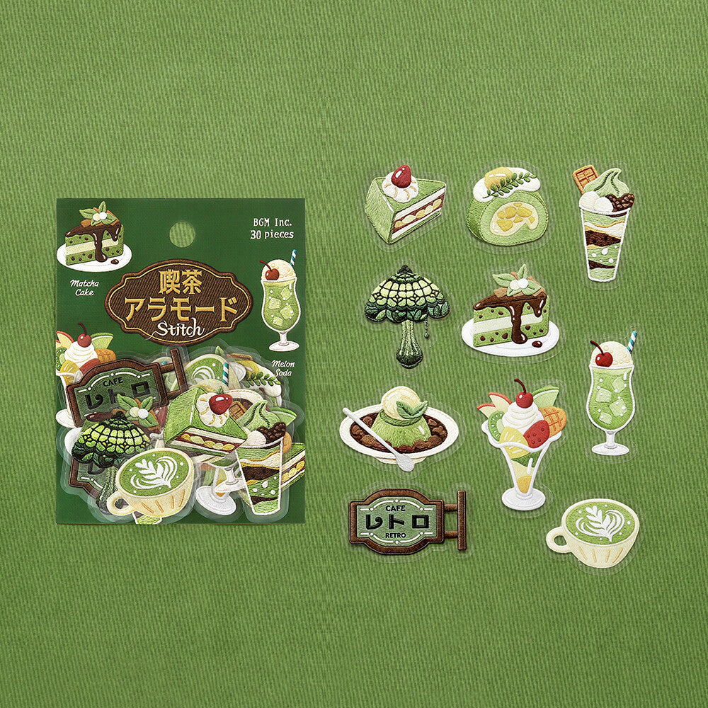 A set of Cafe themed stickers displayed next to their packaging on a textured green background. The stickers feature various retro-themed desserts, drinks, and signage in shades of green, cream, and red.