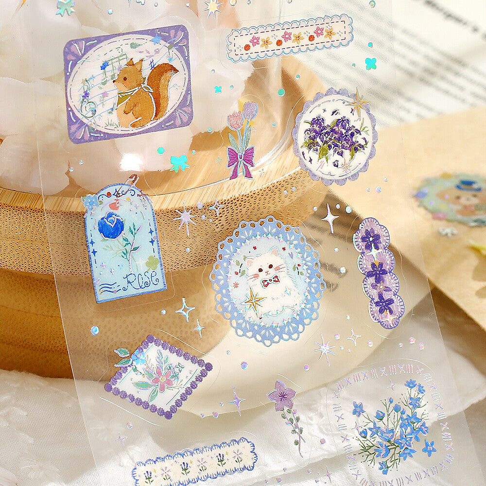 A sticker sheet package featuring purple pastel cartoon illustrations and small decorative elements, shown with a wooden object in the background