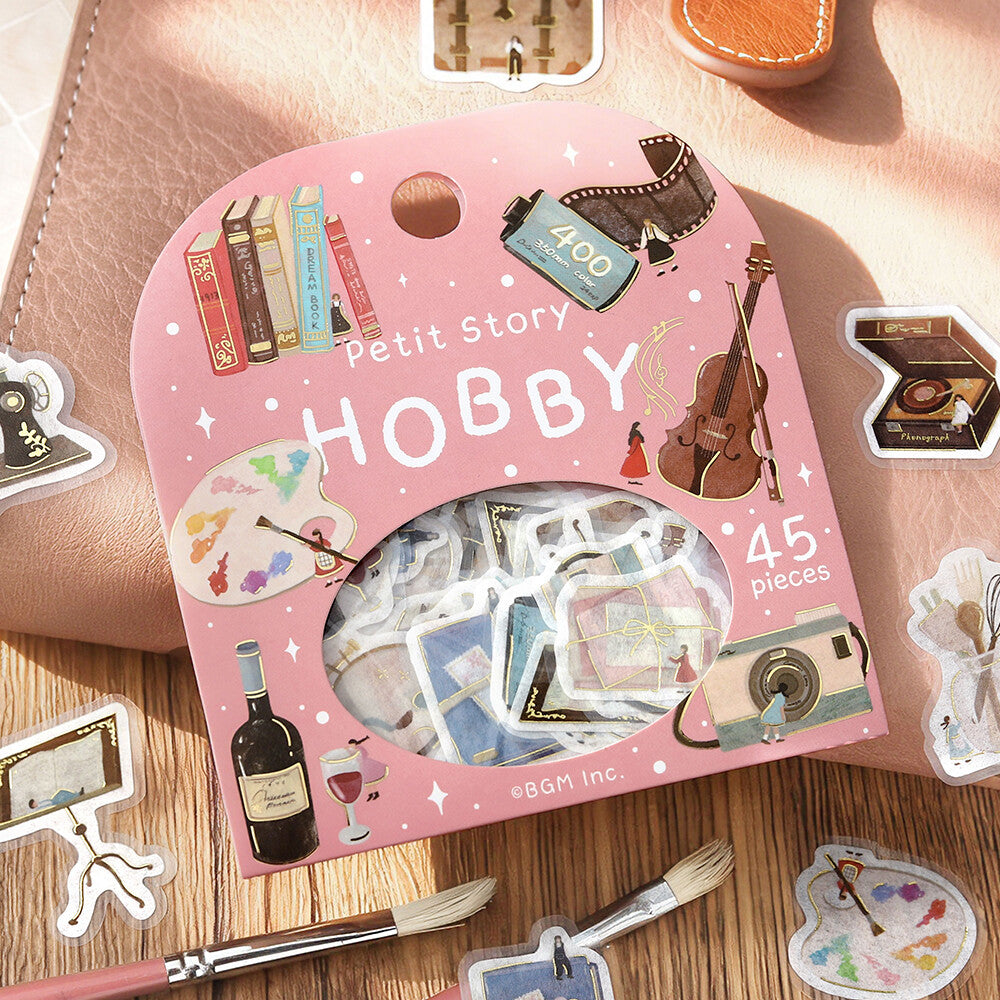Pink 'Petit Story Hobby' sticker set with various stickers on a wooden surface.