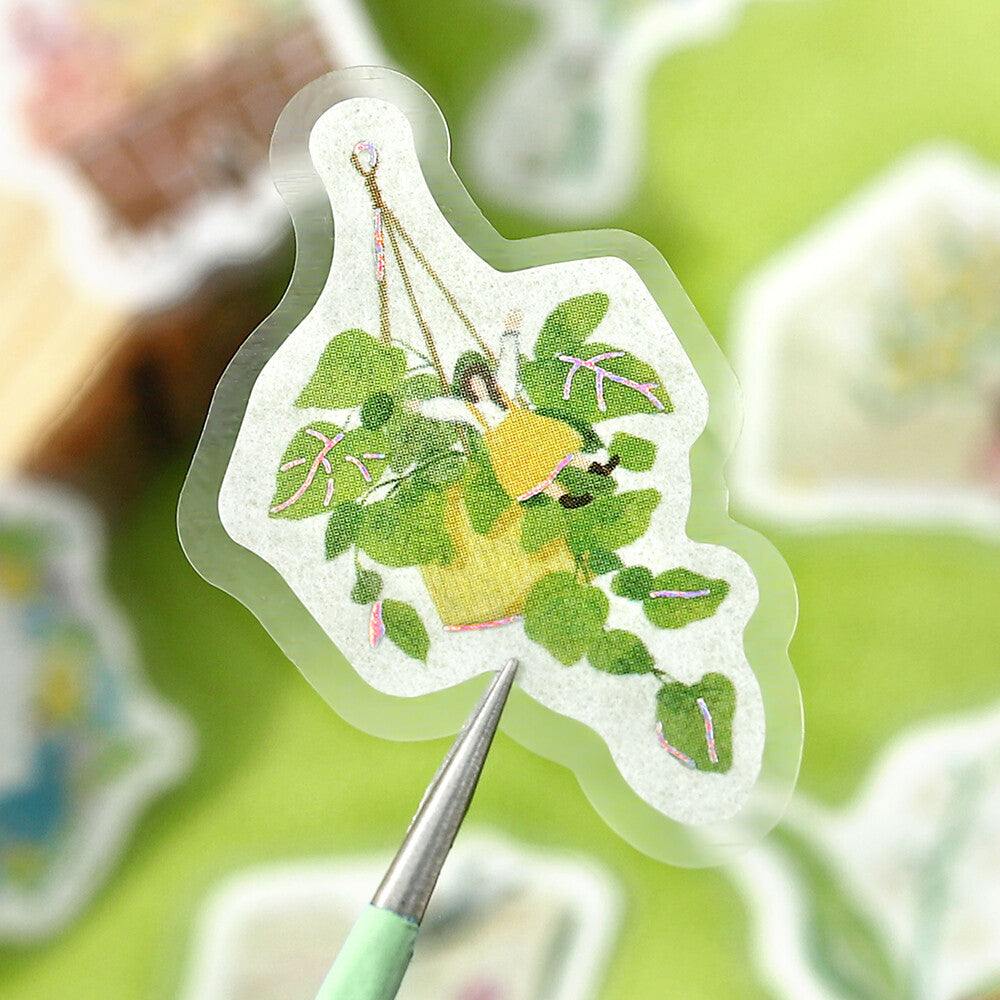 Decorative sticker with a plant design held by tweezers on a blurred background
