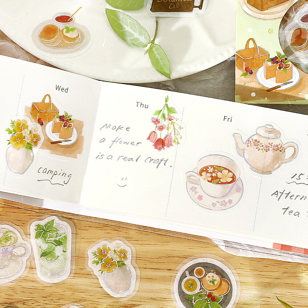 Illustrated planner stickers with tea, flowers, and food on a wooden surface