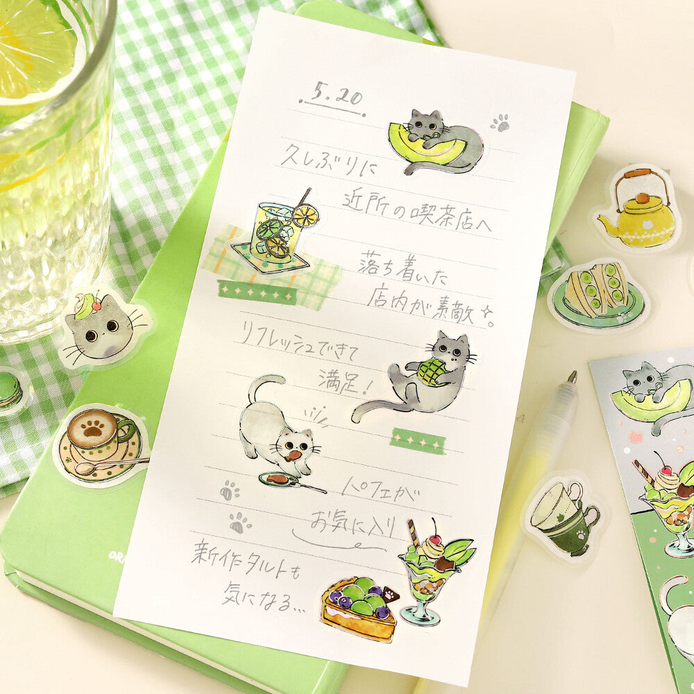 Notebook with cat-themed stickers on a table with a glass of lemonade.