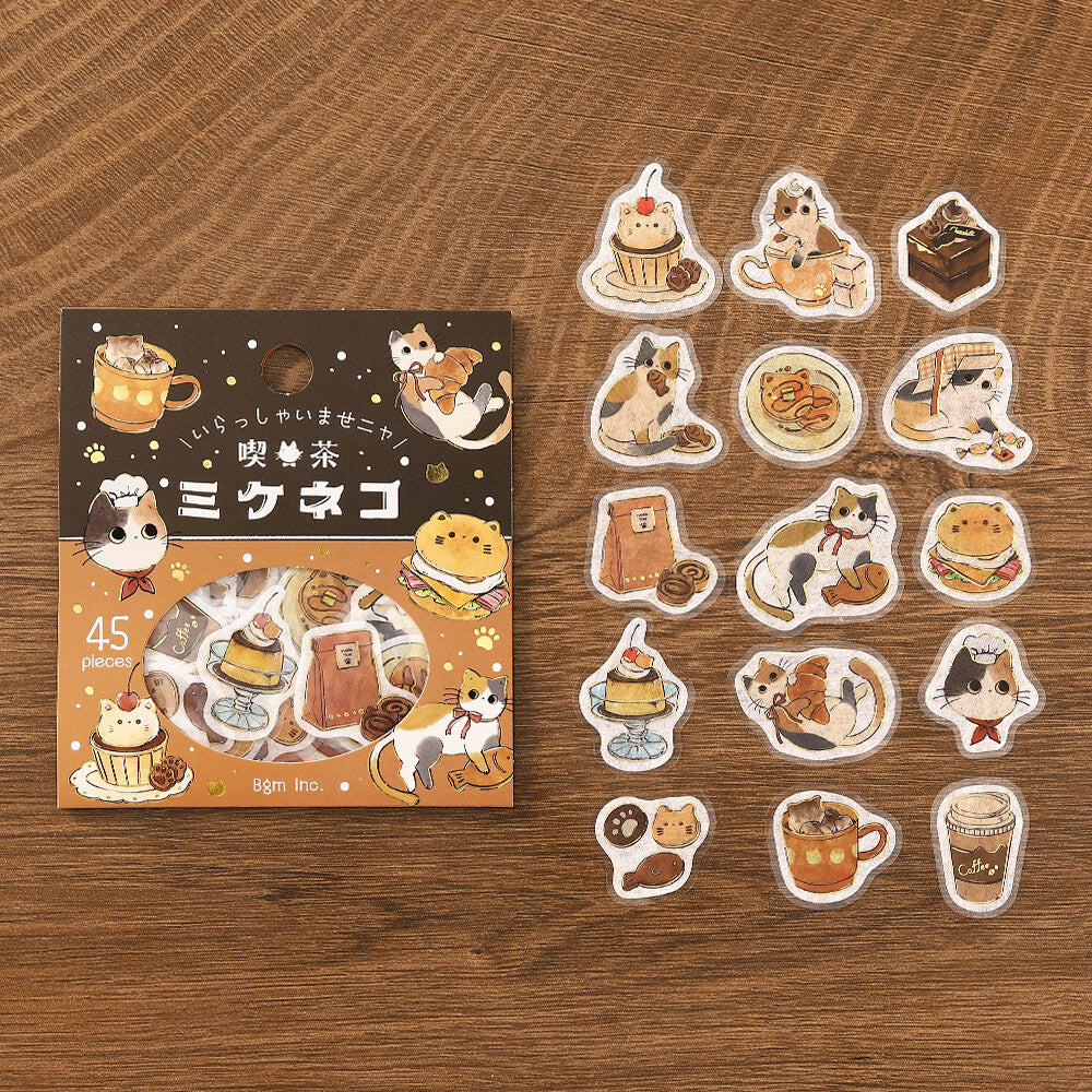 Set of cat-themed stickers with a packaging box on a wooden surface