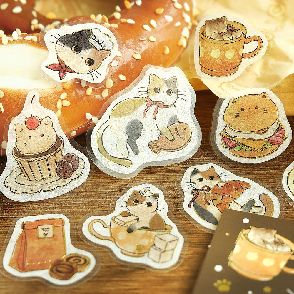 Set of cute cat-themed stickers on a wooden surface with a donut in the background.
