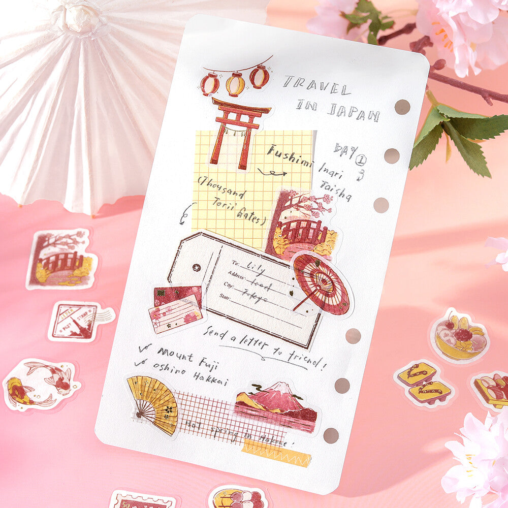 Card with Japanese-themed illustrations and text on a pink background with cherry blossoms and an umbrella.