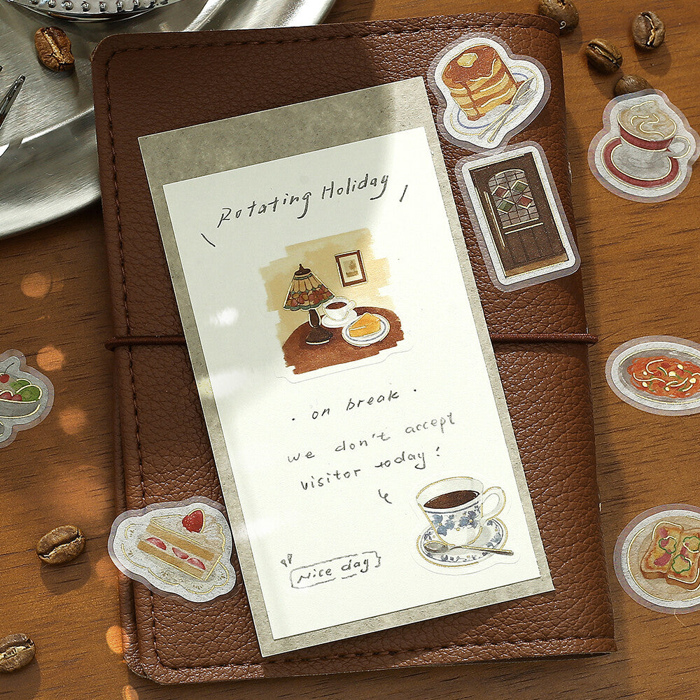 Brown leather notebook with a decorative bookmark featuring illustrations on a wooden surface.