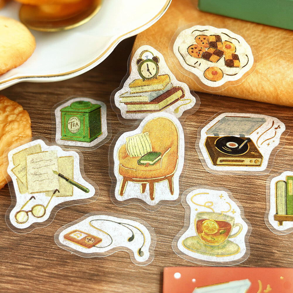 A close-up of a sliced bread or pastry topped with cute illustrated stickers, surrounded by more matching sticker designs on a wooden surface.
