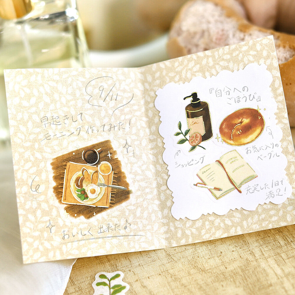 A close-up of a breakfast pastry topped with cute illustrated stickers, surrounded by more matching sticker designs on a card

