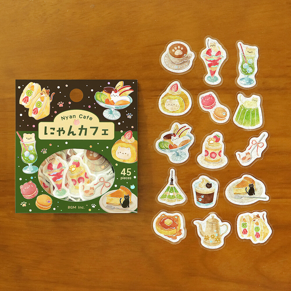 A set of Cafe themed stickers displayed next to their packaging on a textured wood background. The stickers feature various retro-themed desserts, drinks, and signage in shades of green, cream, and red.