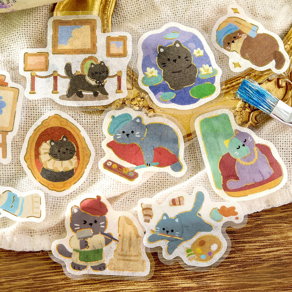 A close-up of cute illustrated stickers of cats, surrounded by more matching sticker designs on a wooden surface.

