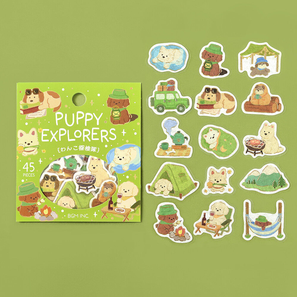 A set of puppy themed stickers displayed next to their packaging on a textured green background. The stickers feature various puppies doing puppy activities, such as sleeping, camping and eating
