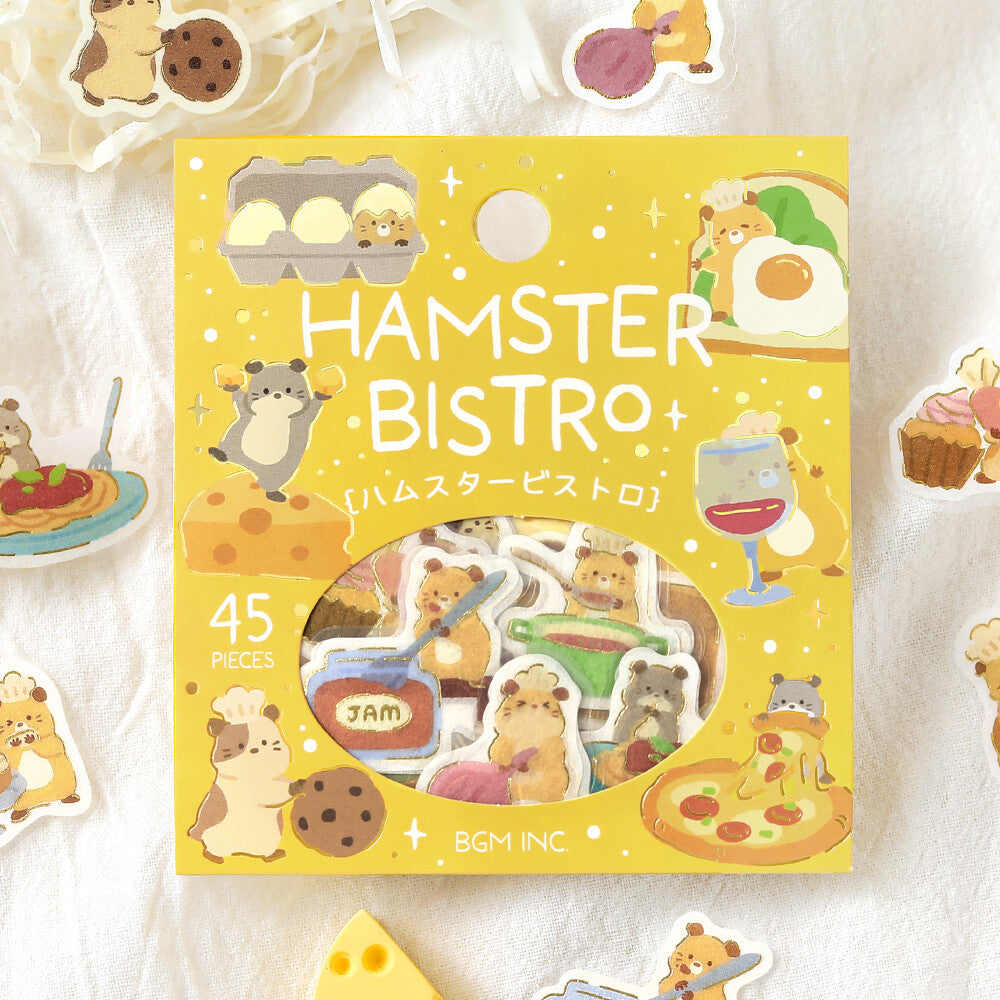 A package of 45 cute hamster-themed stickers displayed on a white textured fabric background. The packaging is bright yellow with illustrations of hamsters in a bistro setting, and the clear window reveals the assorted stickers inside.