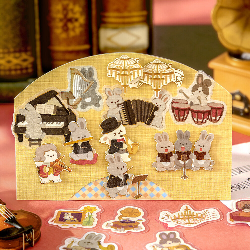A close-up of illustrated stickers, featuring rabbits playing musical instruments, surrounded by more matching sticker designs on a textured red surface.
