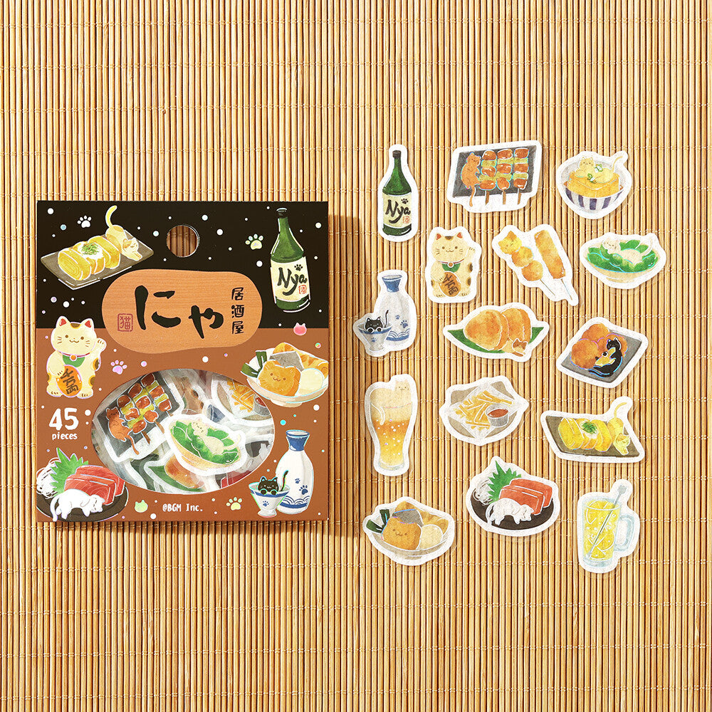 A set of Izakaya themed stickers displayed next to their packaging on a textured bamboo background. The stickers feature various retro-themed skewers, drinks and snacks