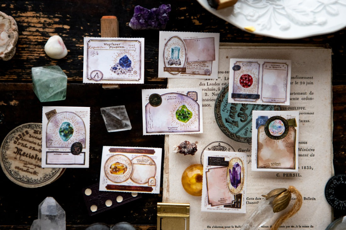 Labels with illustrations of gems in watercolour inks set with gems and antiques in the background