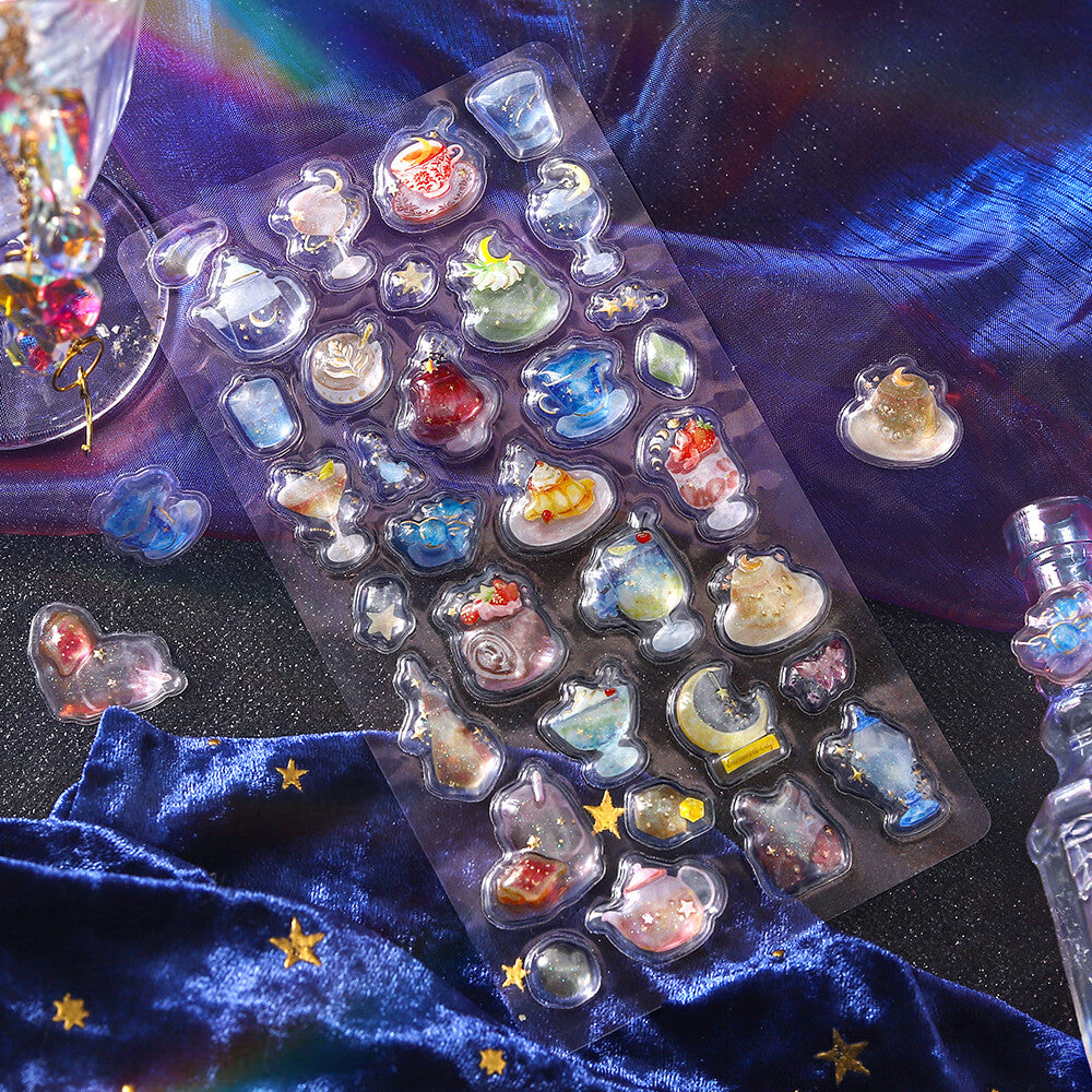 Collection of small decorative items in clear plastic packaging on a dark blue fabric background.