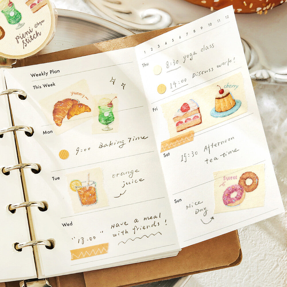 Weekly planner with illustrated stickers of food and activities on a wooden surface.