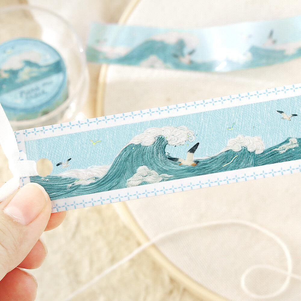 Washi tape with ocean and bird design held by a hand
