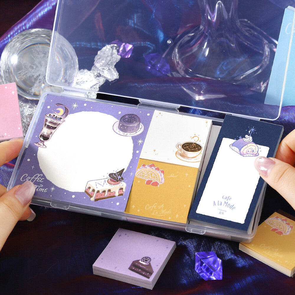 Two hands opening a clear package of memo pads. The memo pads are decorated with a purple sparkly coffee theme on a purple background