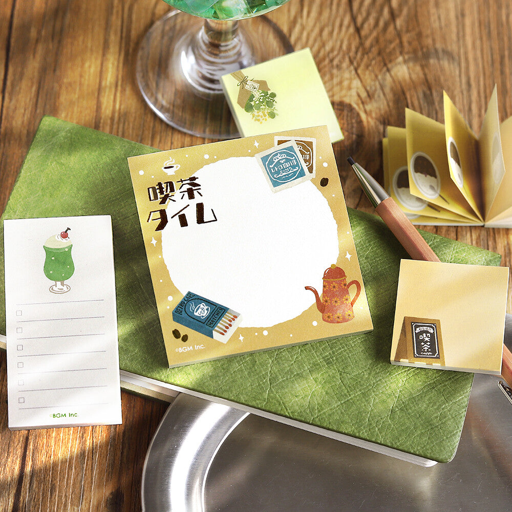 4 decorative memo pads with illustrations on them, against a wooden background