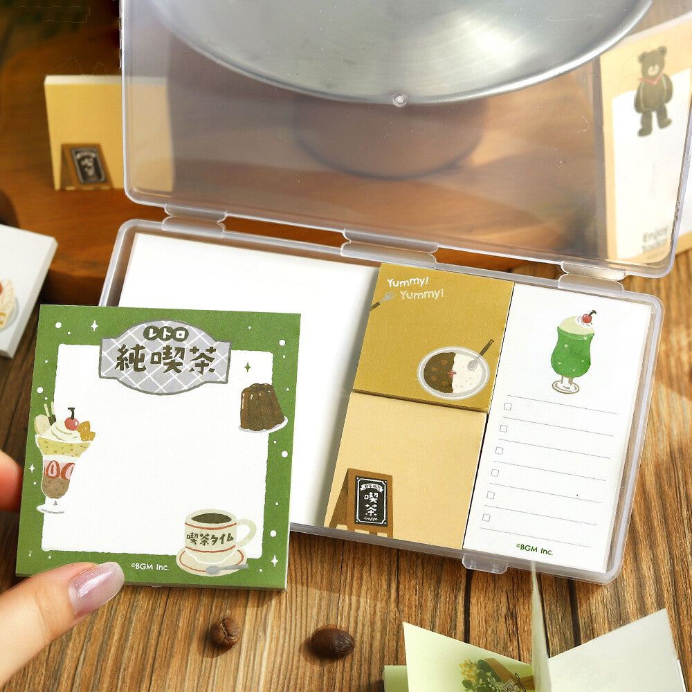 A hand opening a clear package of memo pads. The memo pads are decorated with a restaurant theme on a wood surface