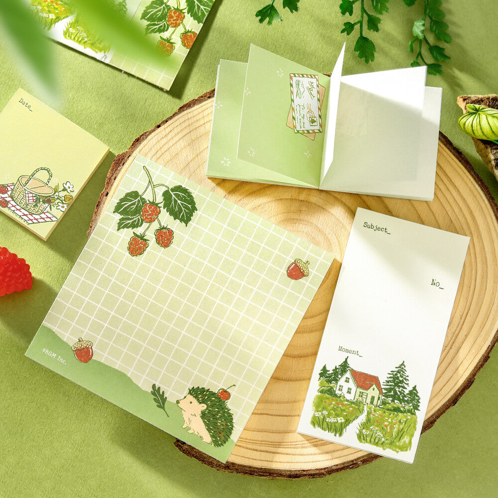 Decorative memo pads with a green theme on a wood surface