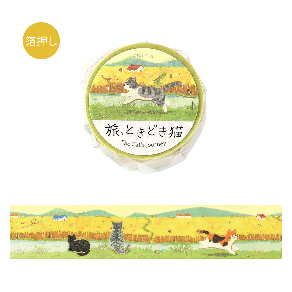 A roll of decorative tape wrapped in clear plastic with a circular label reading 'The Cat's Journey,' shown above an unwrapped strip of the same design. The tape features cats in a wheat field in the sun
