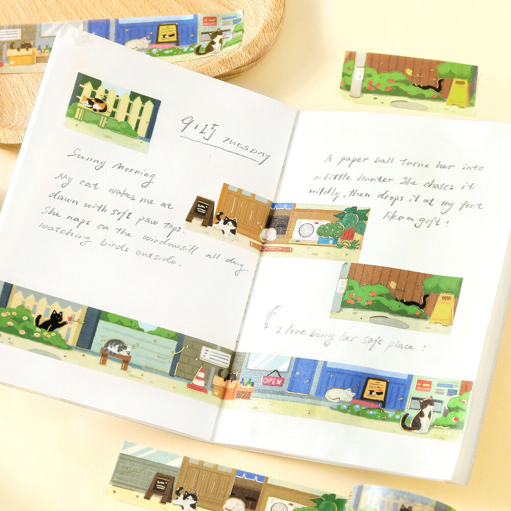 A open page decorated with washi tape featuring cats sitting on the street, napping and playing