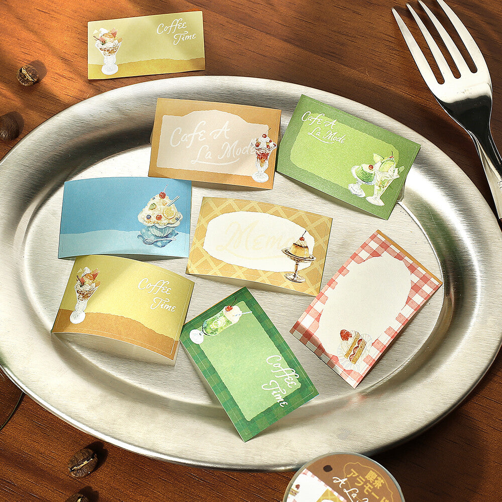 Set of colorful place cards on a metal tray with a fork and wooden surface.